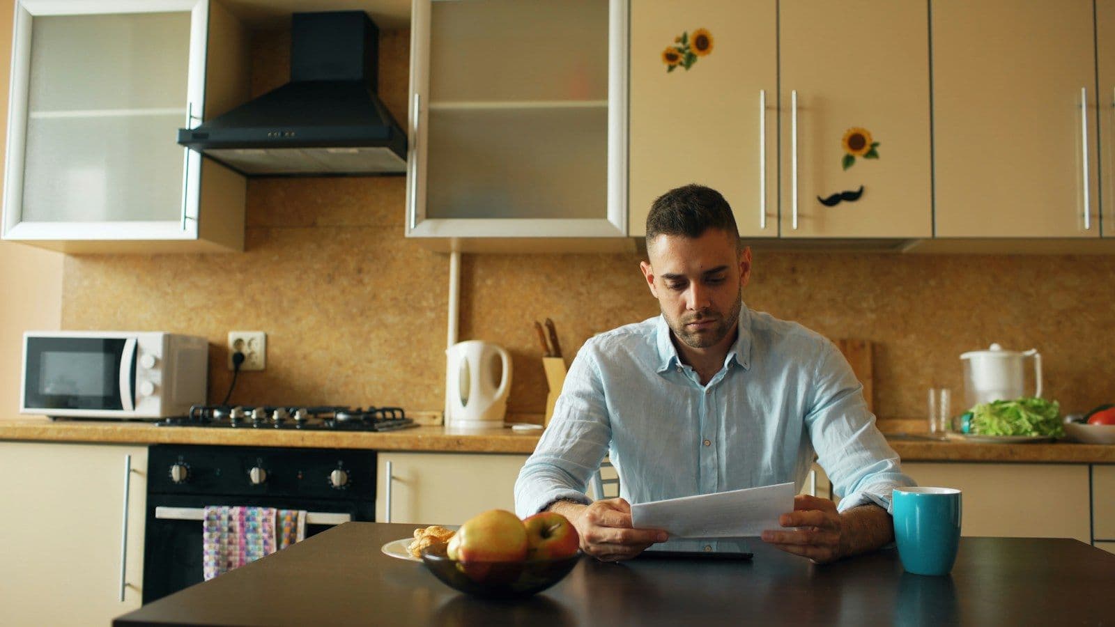 A man sits at his kitchen table reading through a document